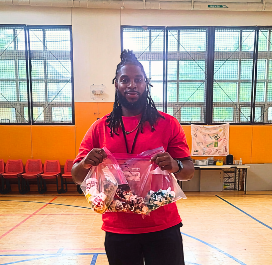Greg Green holding tie-dye t-shirts in a gym