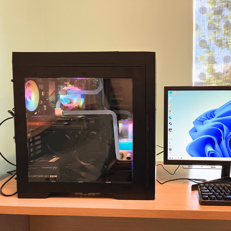 A black PC with a window to see the inner workings, including a water cooling tube and rainbow lights.