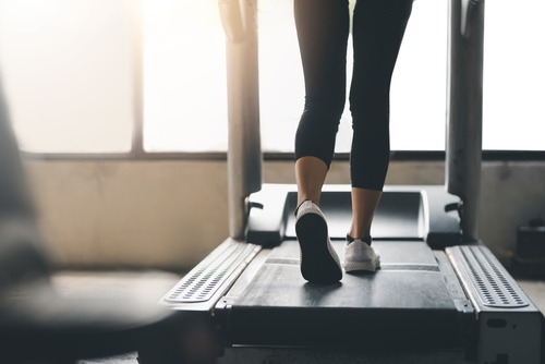 Close up. Woman running in machine treadmill at fitness gym club.