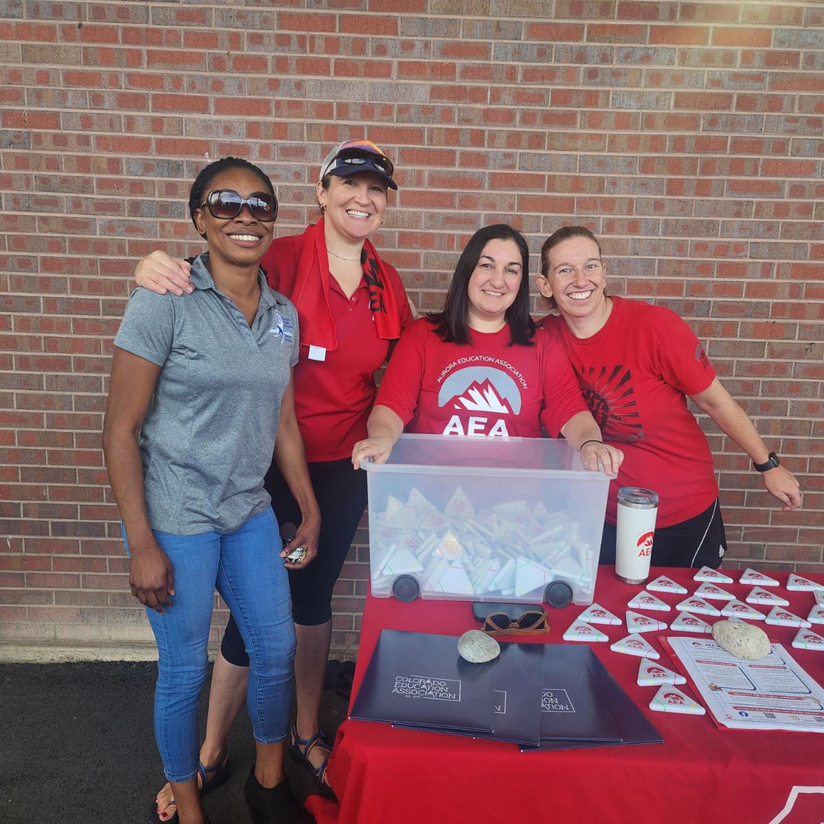 Board President Dr. Anne Keke (left) visits the AEA table at the APS Grand Reopening, with AES President Linnea Reed-Ellis and AEA teachers.