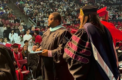 Board President Tramaine Duncan prepares to hand out a diploma at an APS graduation ceremony