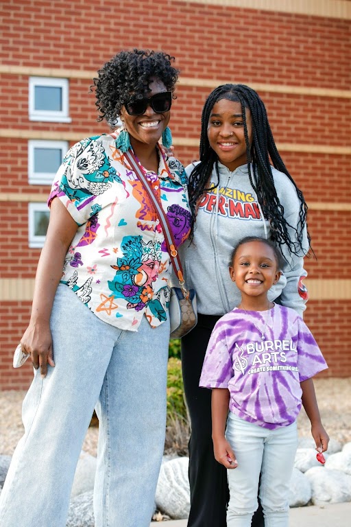 parent posing with her two students outside school