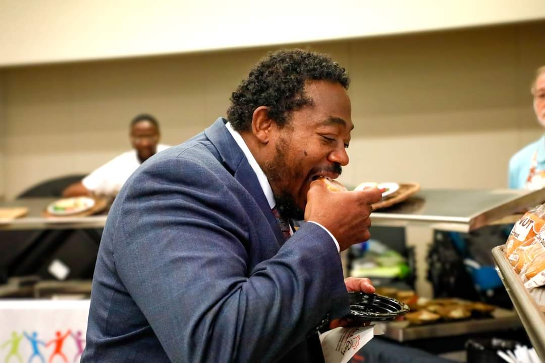 Board Director Michael Carter sampling food at the Aurora Meet and Eat event