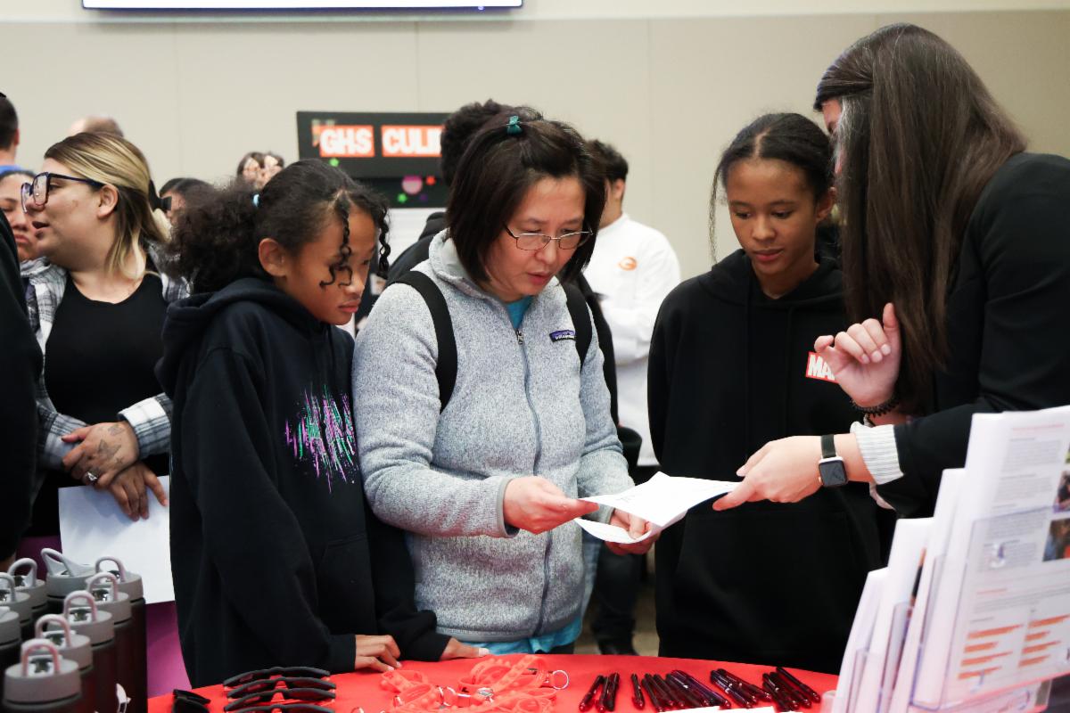 A parent and her students explore information at one of the school fair booths.