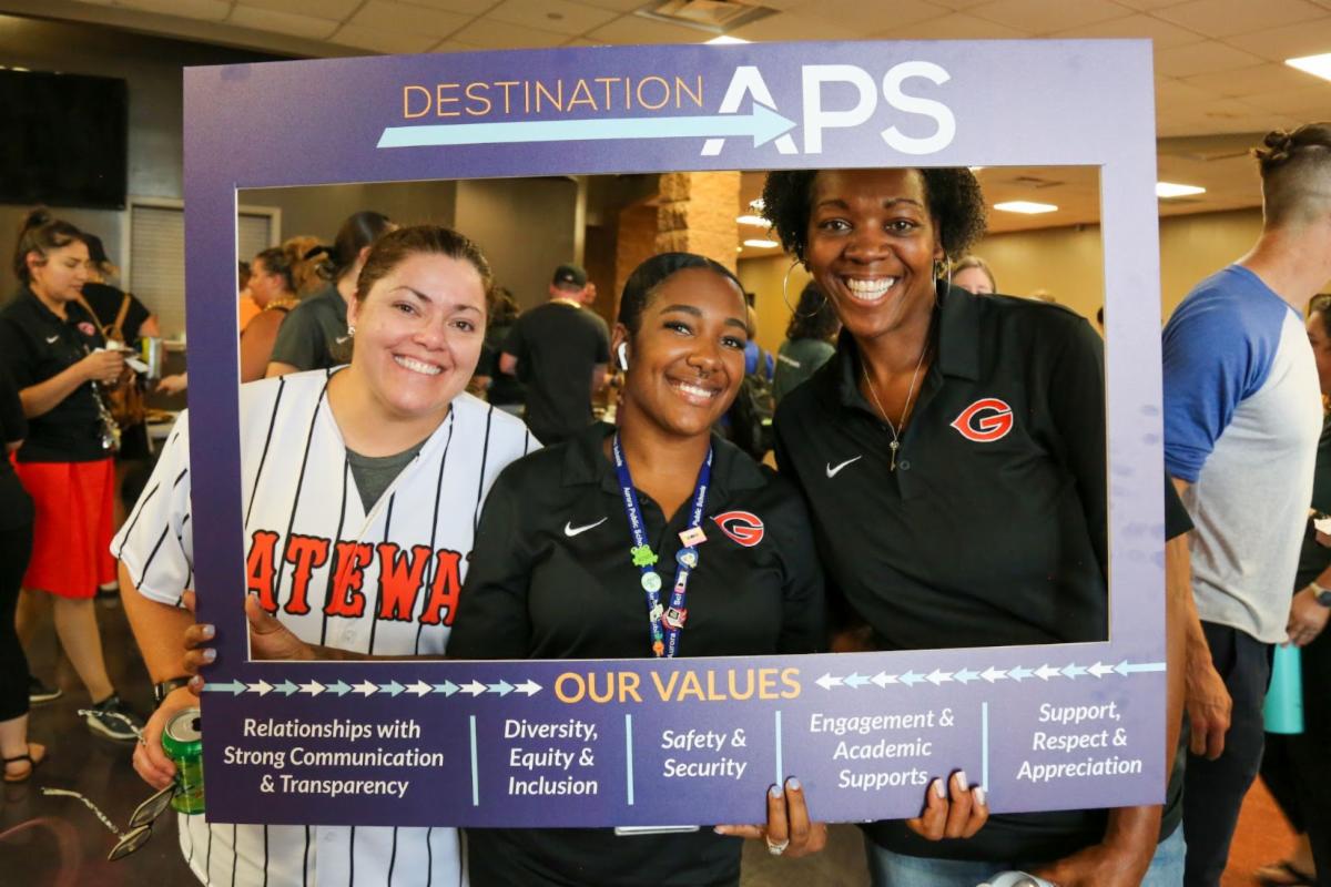 three aps staff members holding up a Destination APS strategic plan sign