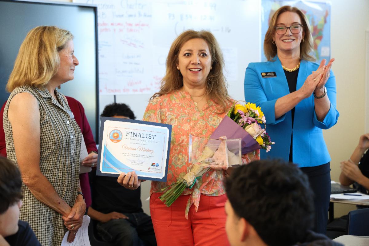 Viviana Martinez holds her finalist certificate and flowers while two other staff members congratulate her.]