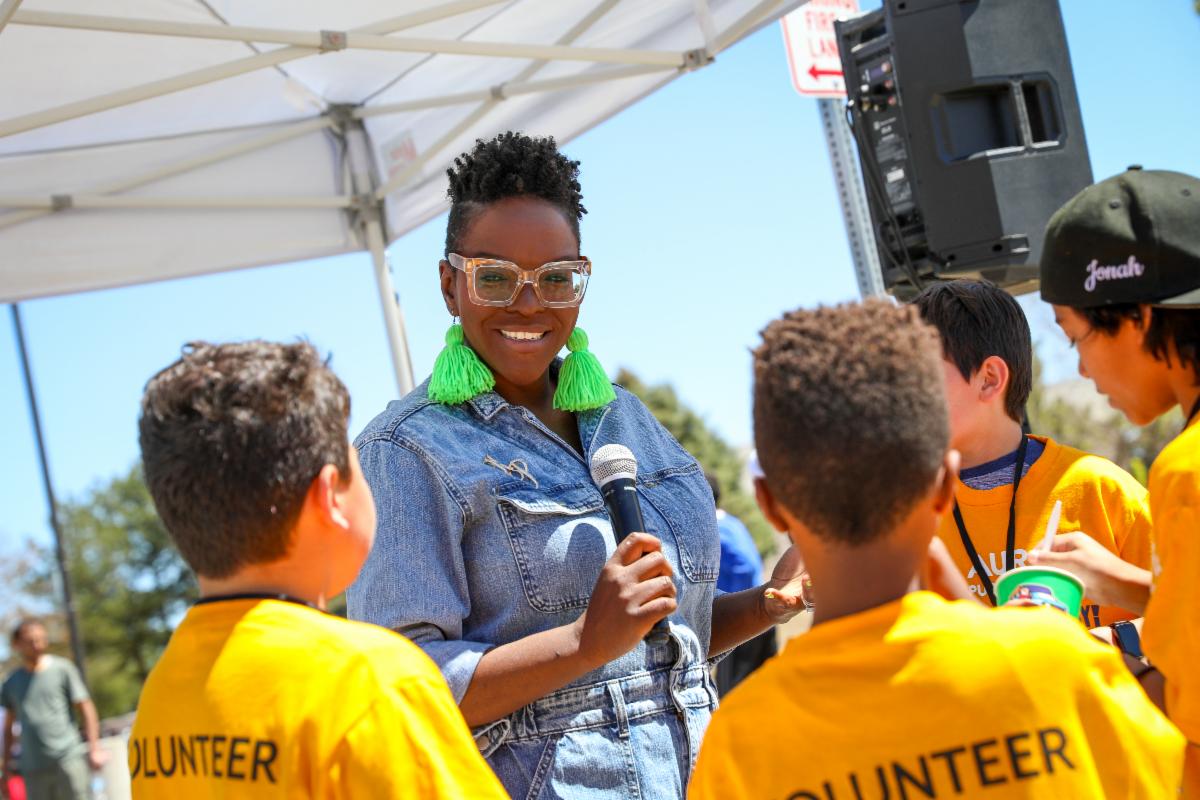 a performer with a microphone speaks to APS students