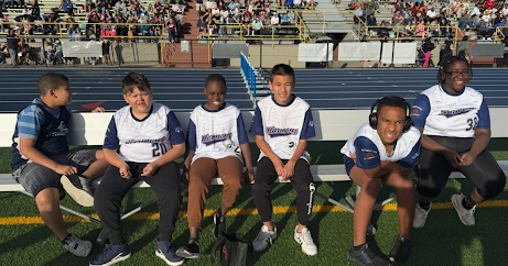 five Unified Sports students sitting on a bench waiting for the event at the Track and Field tournament