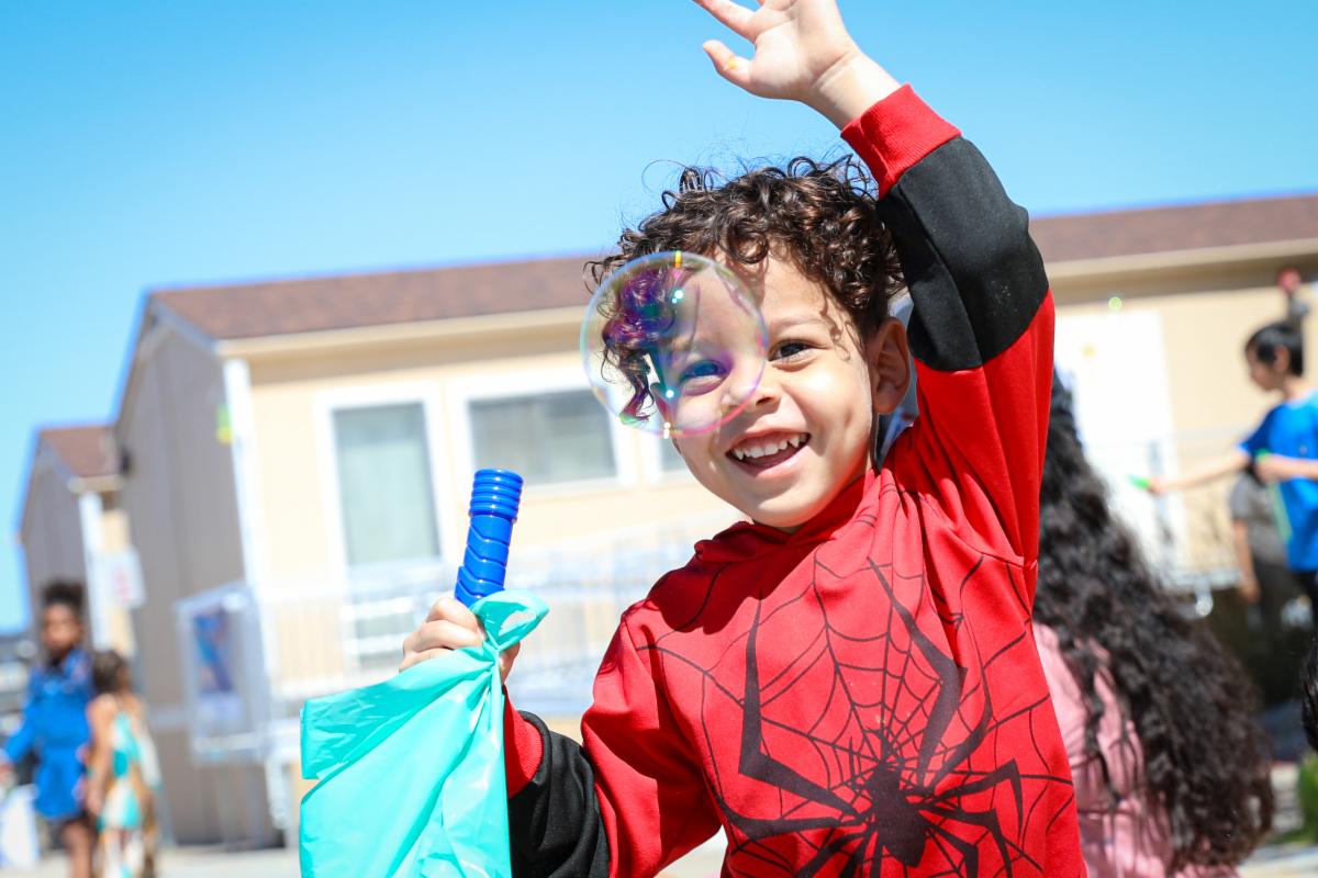 A smiling young student playing outside with bubbles