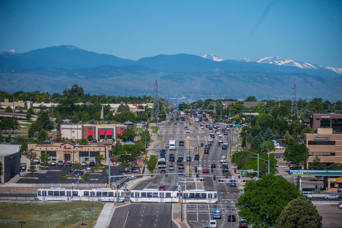 This image of a city with a road, buildings, a light rail train, cars and mountains links to the city's economic and business development webpage