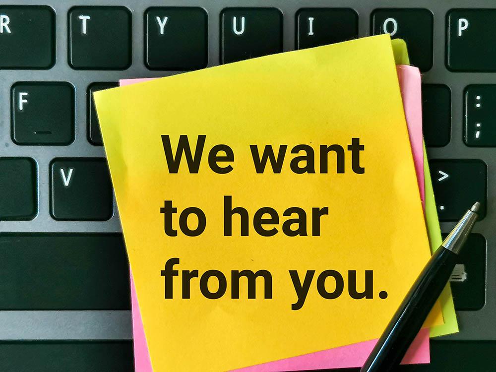 This graphic of a portion of a keyboard with sticky notes and the words We want to hear from you links to an online form