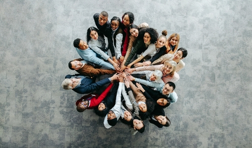Top view of a diverse team of people joining hands in a collaborative and inclusive business environment_ symbolizing unity and teamwork.