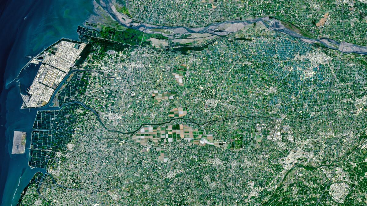 An array of green rectangular parcels of farmland in a range of hues is interspersed with several small towns.