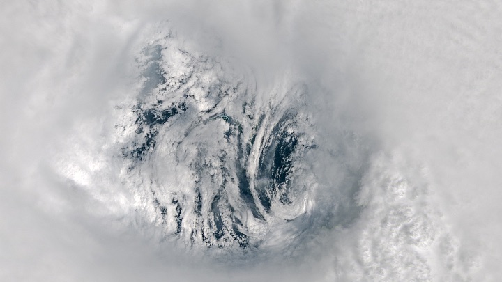 Satellite image of Typhoon Krathon's eye, showing turbulent cloud formations swirling around a center where the ocean is visible. The clouds, in varying shades of white and gray, highlight the atmospheric conditions within the storm. A 10 km scale marker is shown in the bottom left for reference.