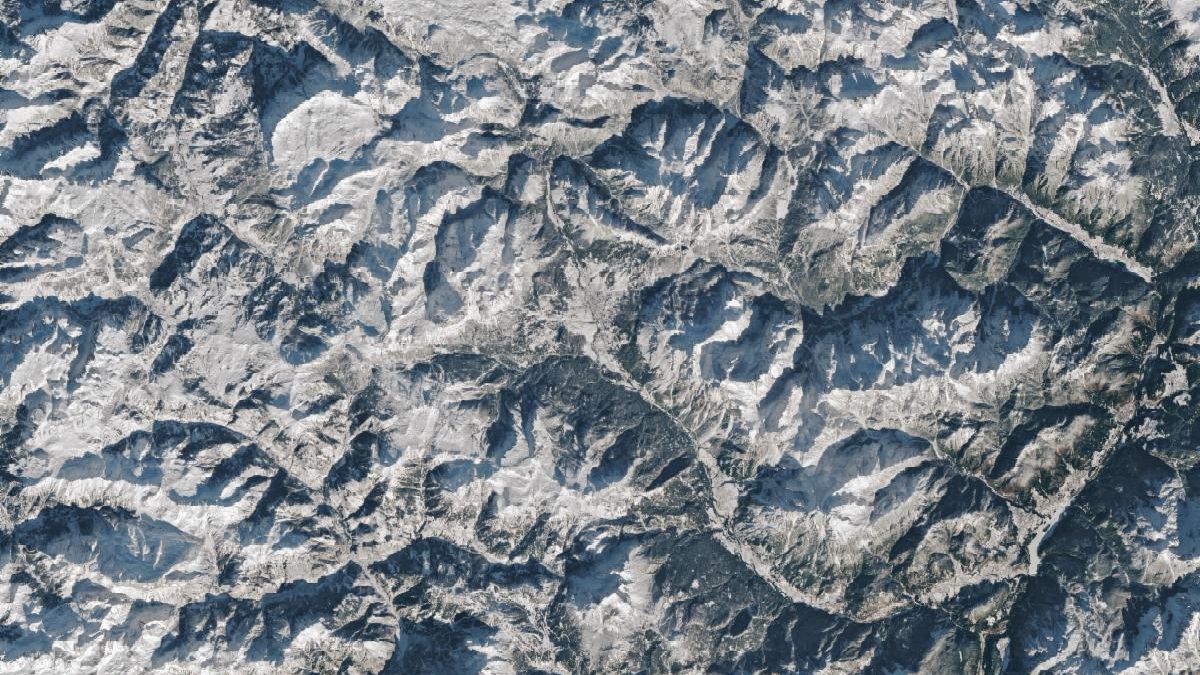 A 3D map shows the town of Cortina d’Ampezzo, Italy, in the foreground with tall peaks in the Dolomites rising behind it. A label indicates the location of the Olympic ski run on a mountain called Tofana di Mezzo. Snow covers the ground in most of the scene.