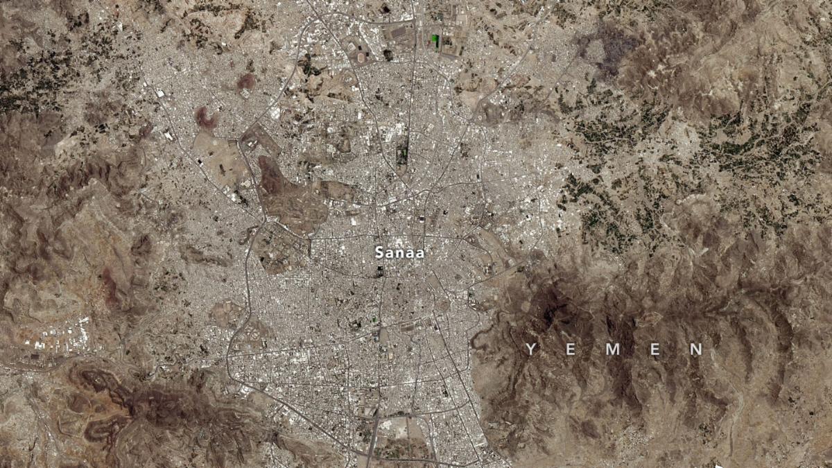 Sanaa, Yemen and surrounding regions, including the airport to the north and mountains on either side. The image is mostly brown and grey, with very little green space in or around Sanaa.