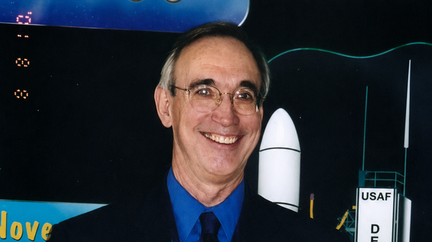 A photograph of John Barker holding an award.
