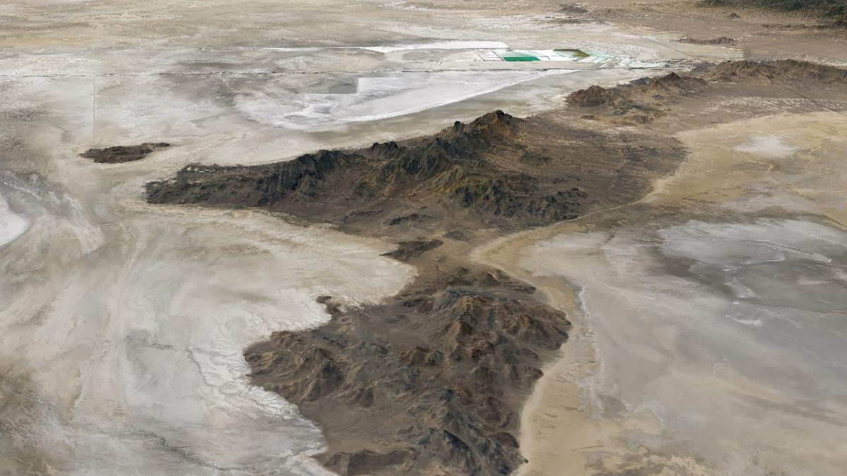 Tan and white plains surround a dark mountainous ridge in a three-dimensional image of the Silver Island Mountains.