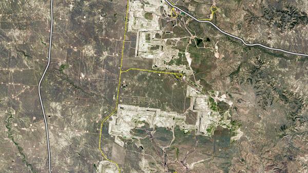 Map of an area with railroad tracks and roads indicated, along with a town and grassland areas