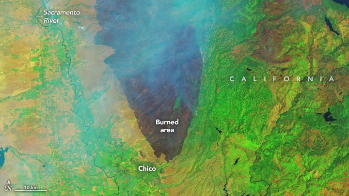 Infrared-color Landsat 9 image of a wildfire in Northern California, acquired on July 27, 2024. The burned area is evident in the false-color image showing shortwave infrared, near infrared, and visible light (band combination 6-5-3). This band combination makes it easier to identify unburned vegetated areas (green) and the recently burned landscape (brown). Thicker areas of the smoke plume appear light blue. White text highlights Burned area, California, Chico, Smoke, Lake Almanor, and the Sacramento River.