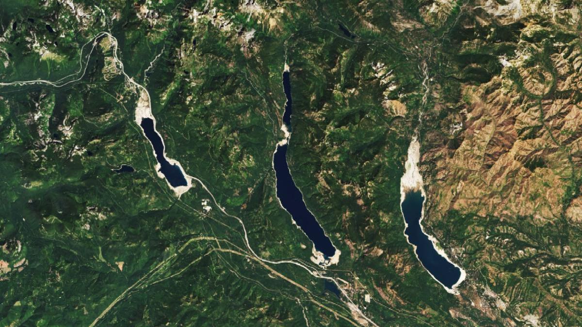 A satellite image shows the three reservoirs in July 2025. At this time water levels were much lower and sandy parched areas are visible around the edges of all three reservoirs.