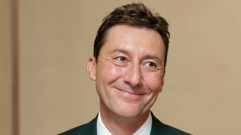 A headshot of a smiling man in a suit