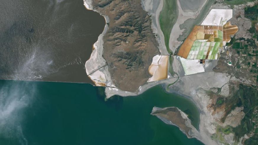 A satellite image of the Great Salt Lake shoreline in 2025 shows exposed gray lakebed with clusters of small dark mounds; an inset provides a close-up view of the mounds.