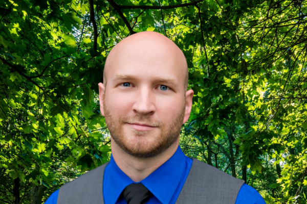bald man with beard and mustache smiles at camera