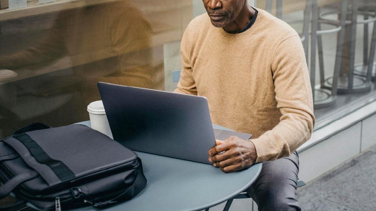 Man in front of laptop at cafe table
