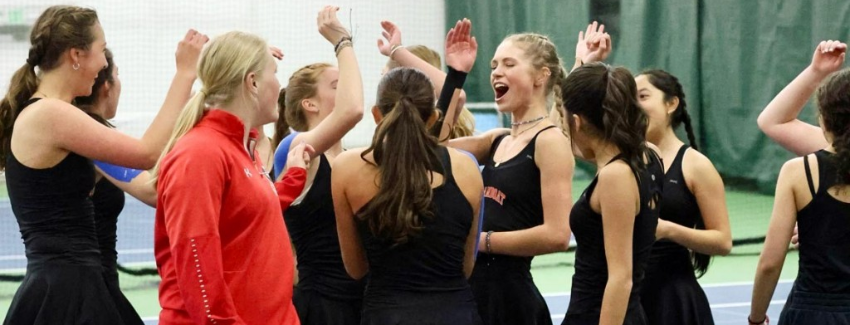group of high school girls high five on a tennis court