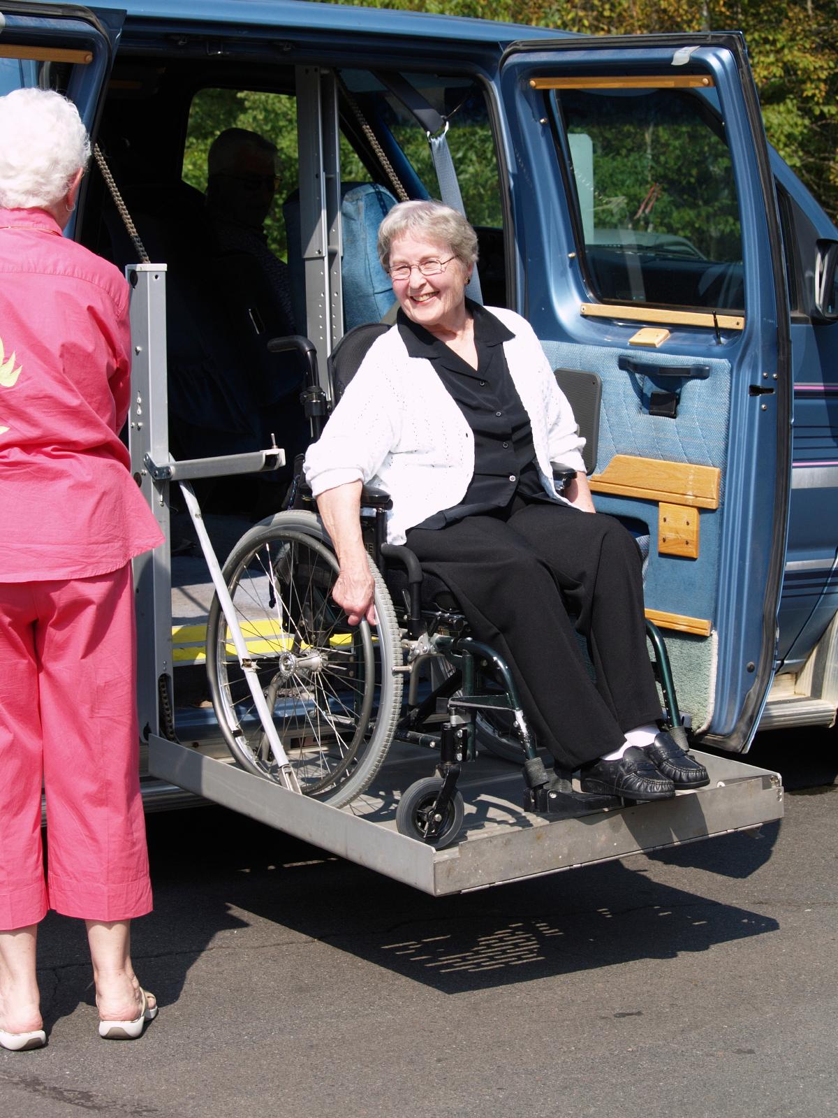 Older woman being unloaded from a van in a wheelchair