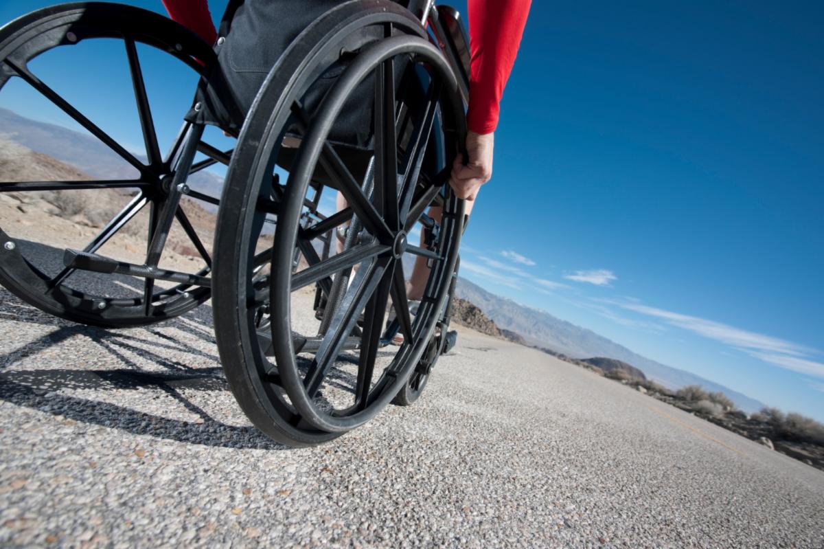 Image of a person propelling themselves in a wheelchair with wide space ahead of them.