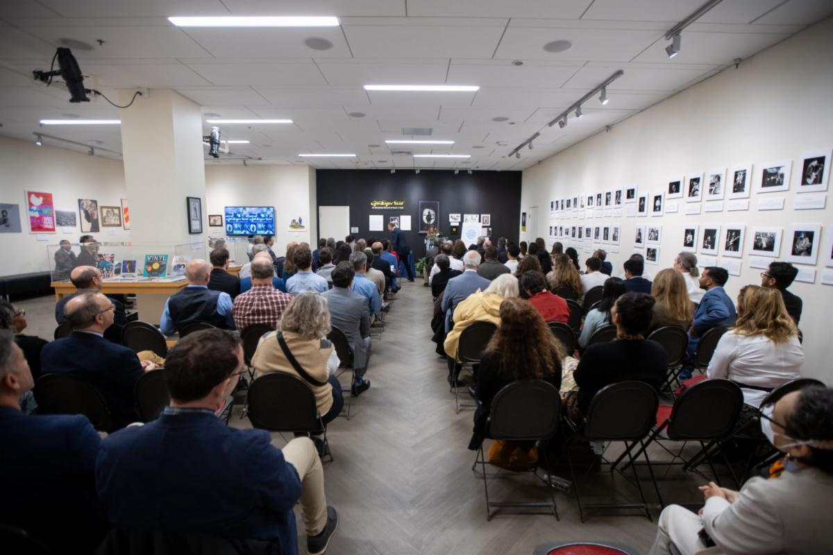 A lecture hall full with people sitting at tables. They are watching the awards being provided to individuals who won the Excellence in Community Engagement Scholarship awards