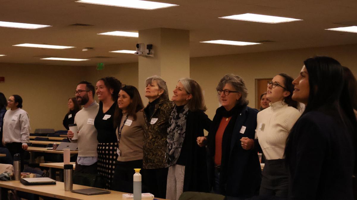 Group of conference attendees standing up and hugging while singing