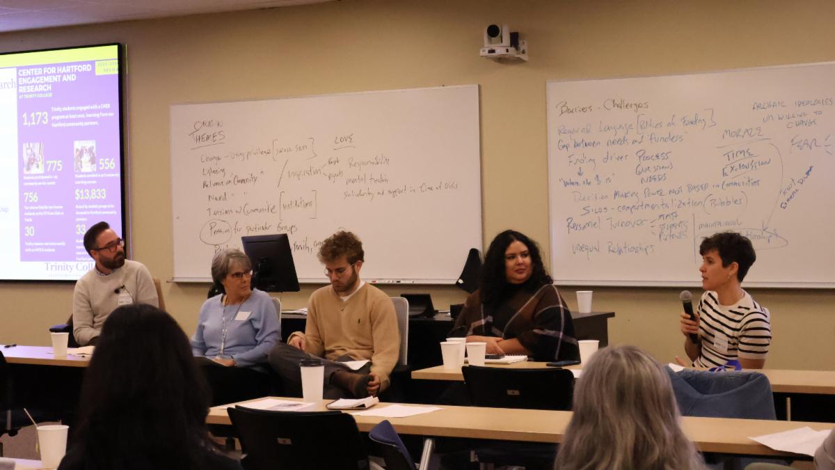 Panelists sitting on chairs talking on microphone