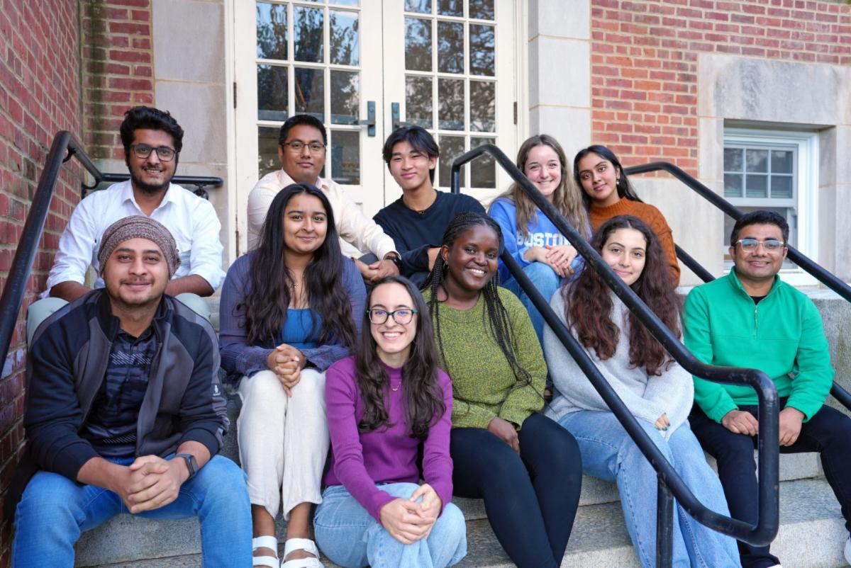 Group of faculty and students sitting together in the stairs smiling. About 11 individuals. 