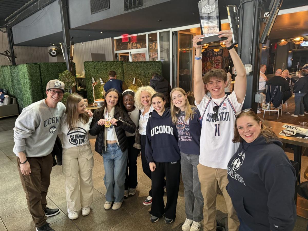 A group of UConn students and adults outside of the basketball arena wearing UConn apparel. 