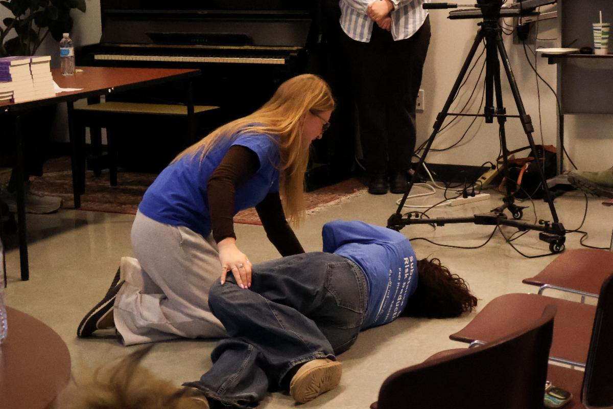 UConn student demonstrating how to provide Naloxone. It's two females. 