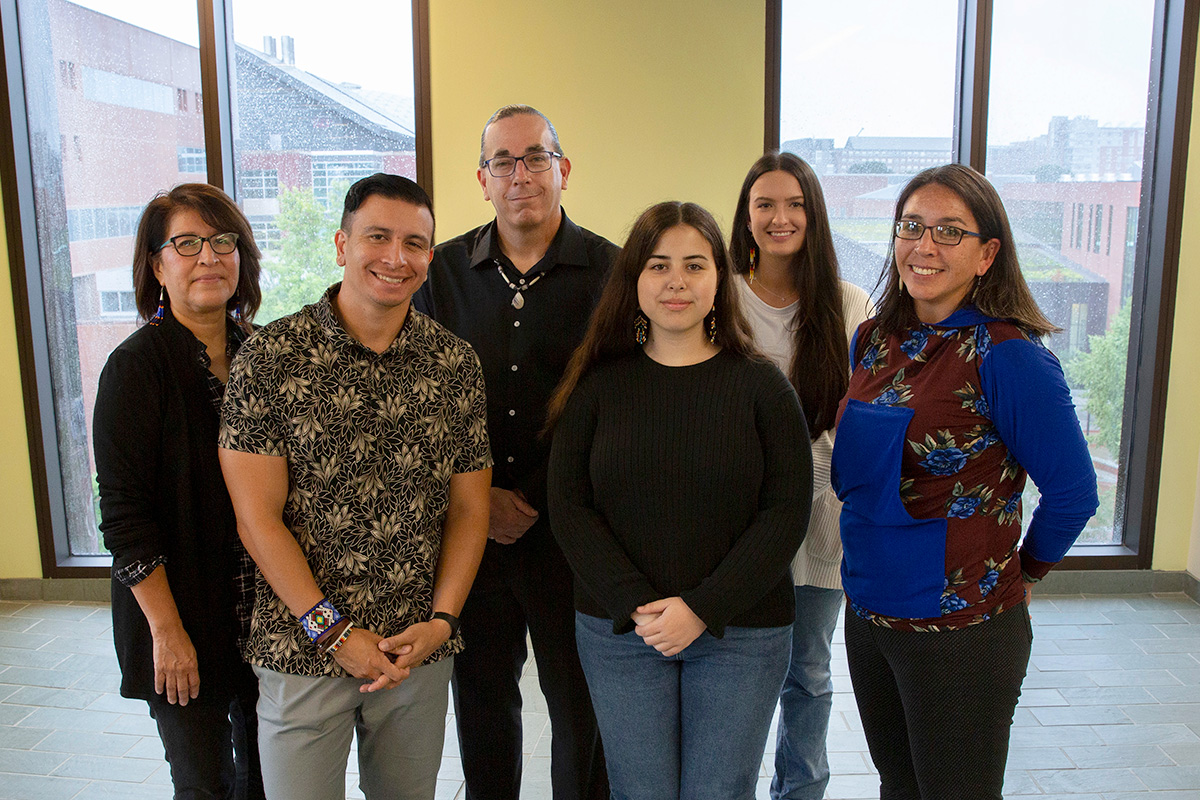 A group 6 people (faculty, staff and students) standing together smiling. 