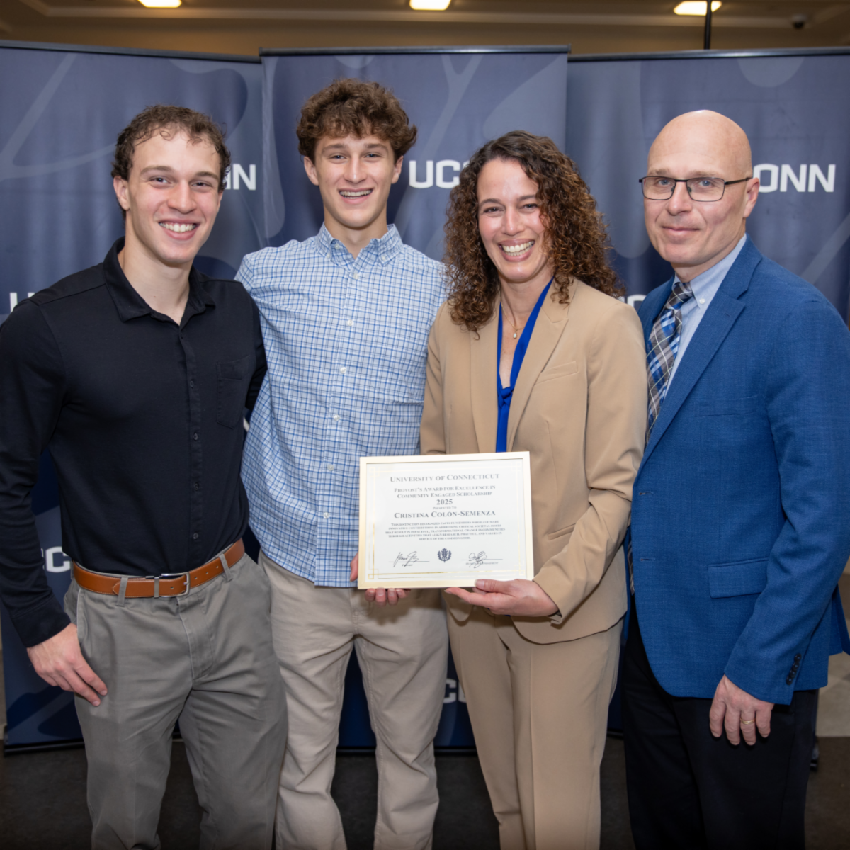 Award Recipient Faculty posing for a photo with her family in front of a UConn sign.