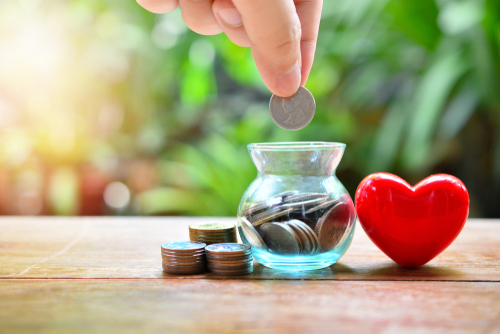putting money coins in glass bottle for concept donation and philanthropy