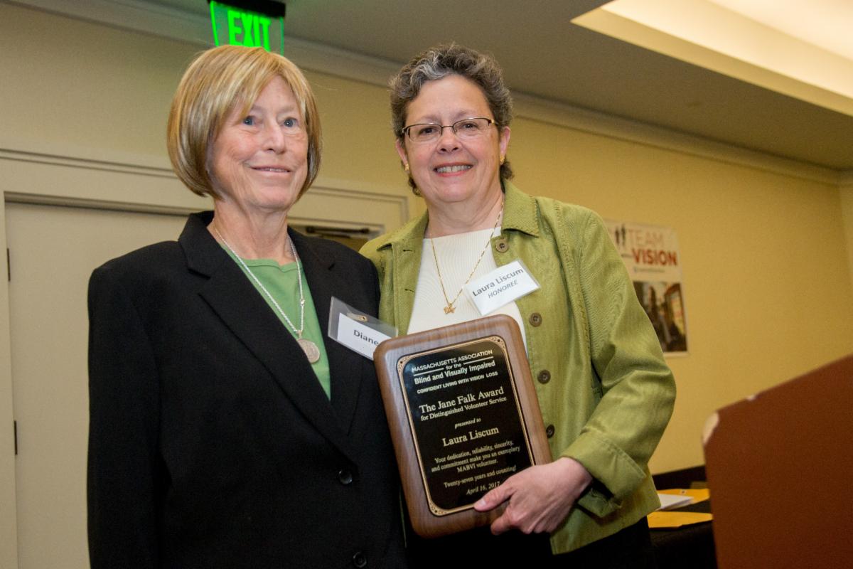 Laura standing next to her consumer and hold an award