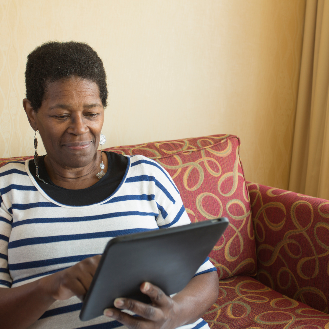 A woman sitting on a couch looking at an iPad