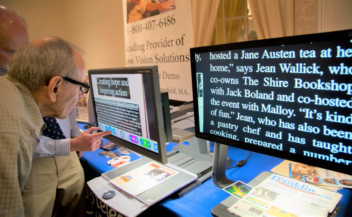 Two people view enlarged text on CCTVs.