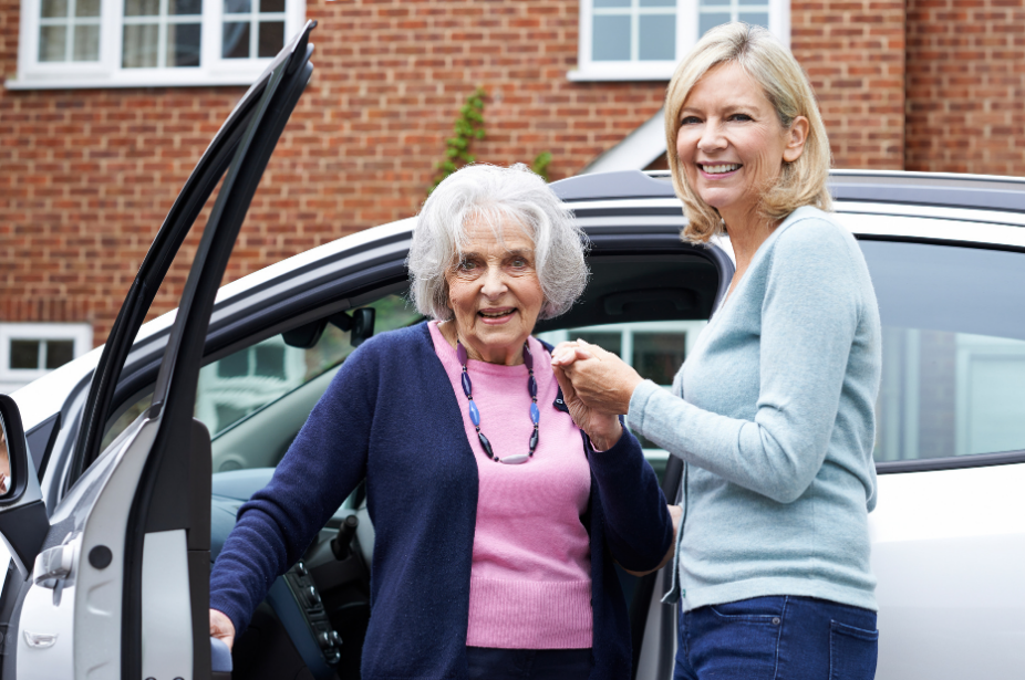an older woman being assisted out of her car by another woman