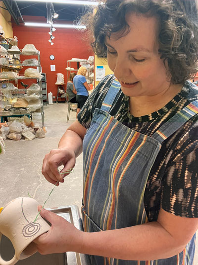 Student pulling tape to reveal design on mug