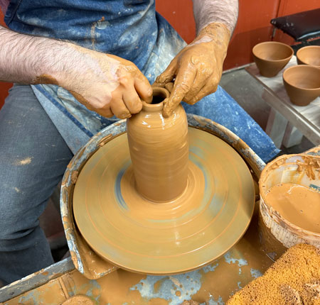 Hands in clay wheel throwing