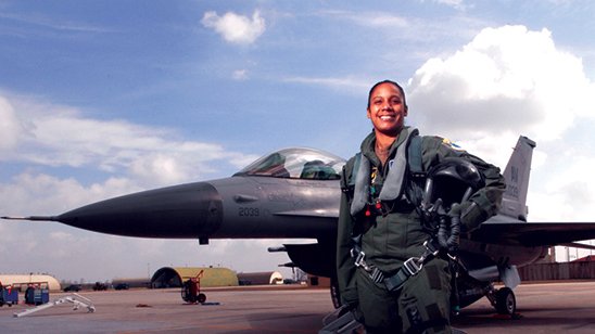 Female fighter pilot stands in front of her plane