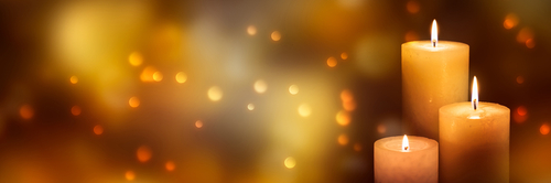 three candle lights at the edge of blurred festive background_ decorative golden shiny candle lights