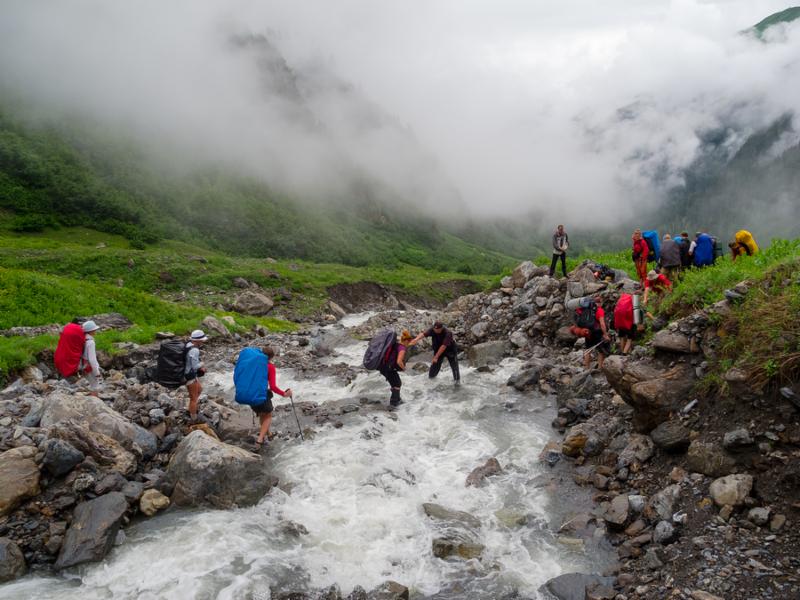 Hikers group cross the mountain river ford